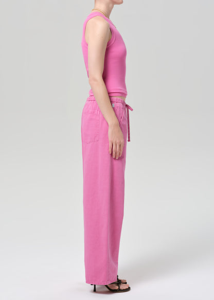 Person wearing a pink sleeveless top and wide-leg pants on a plain background