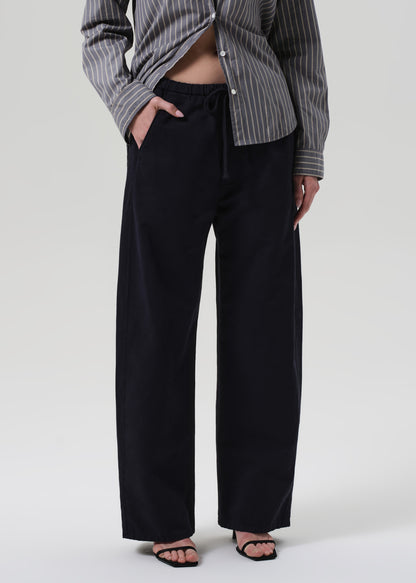 Person wearing a striped shirt and navy pants on a grey background