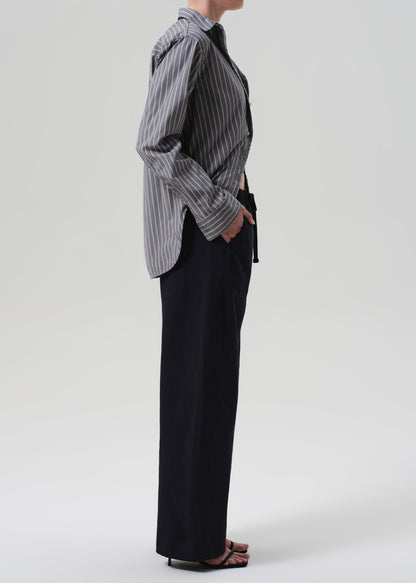 Person wearing a striped shirt and navy pants on a grey background