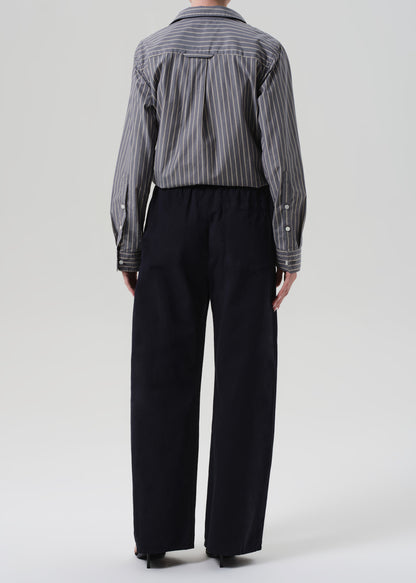 Person wearing a striped shirt and navy pants on a grey background