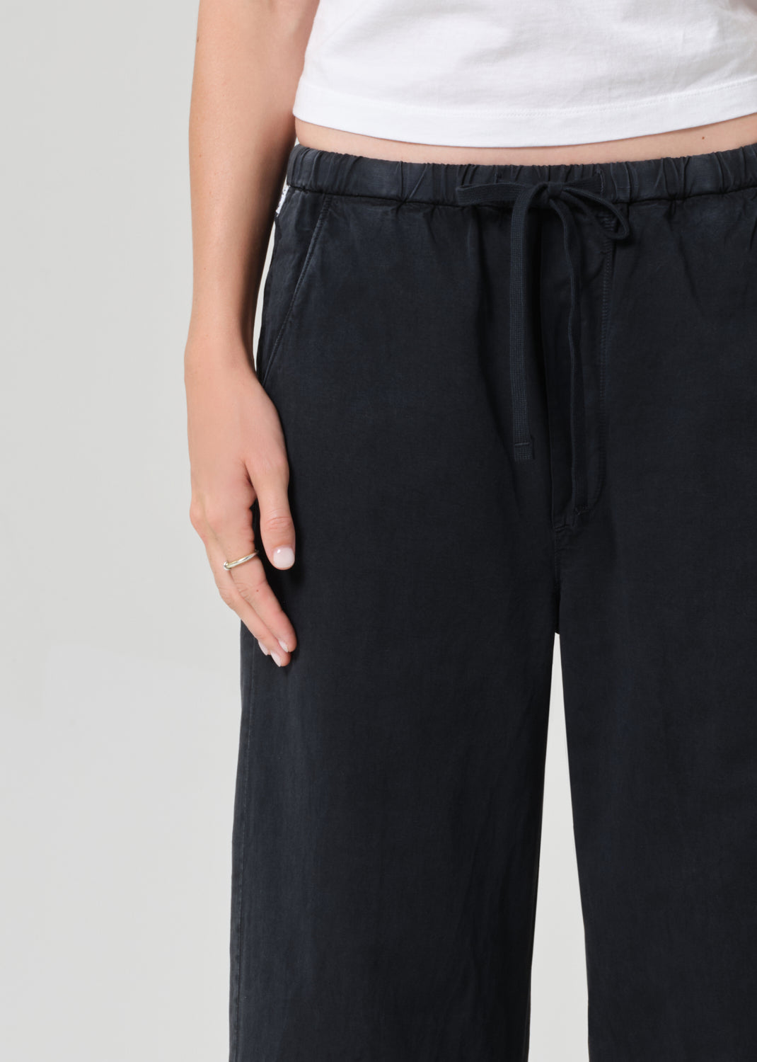 Black wide-leg pants with a white top on a light gray background