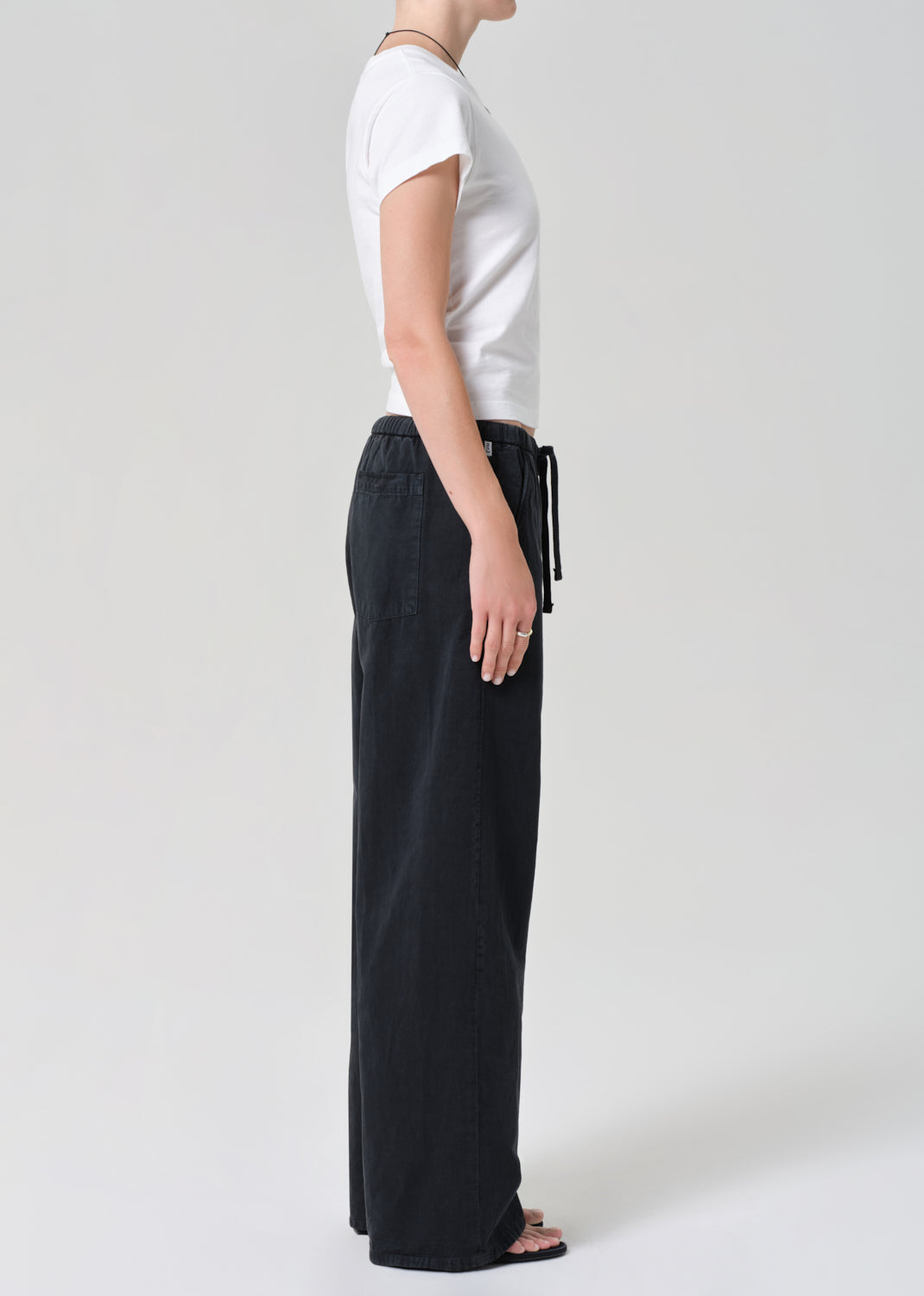 Person wearing a white t-shirt and black wide-leg pants on a plain background