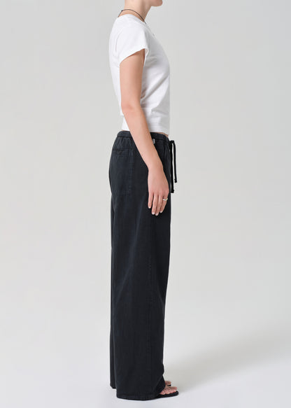 Person wearing a white t-shirt and black wide-leg pants on a plain background