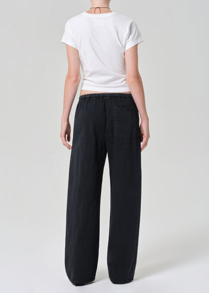 Person wearing a white t-shirt and black wide-leg pants on a light gray background