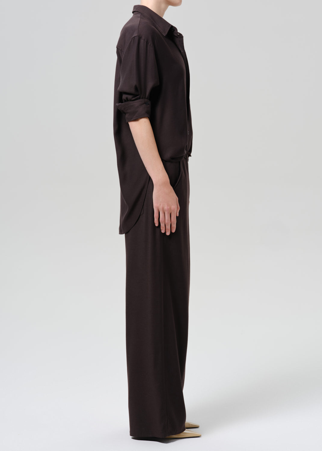 Person wearing a brown outfit on a grey background