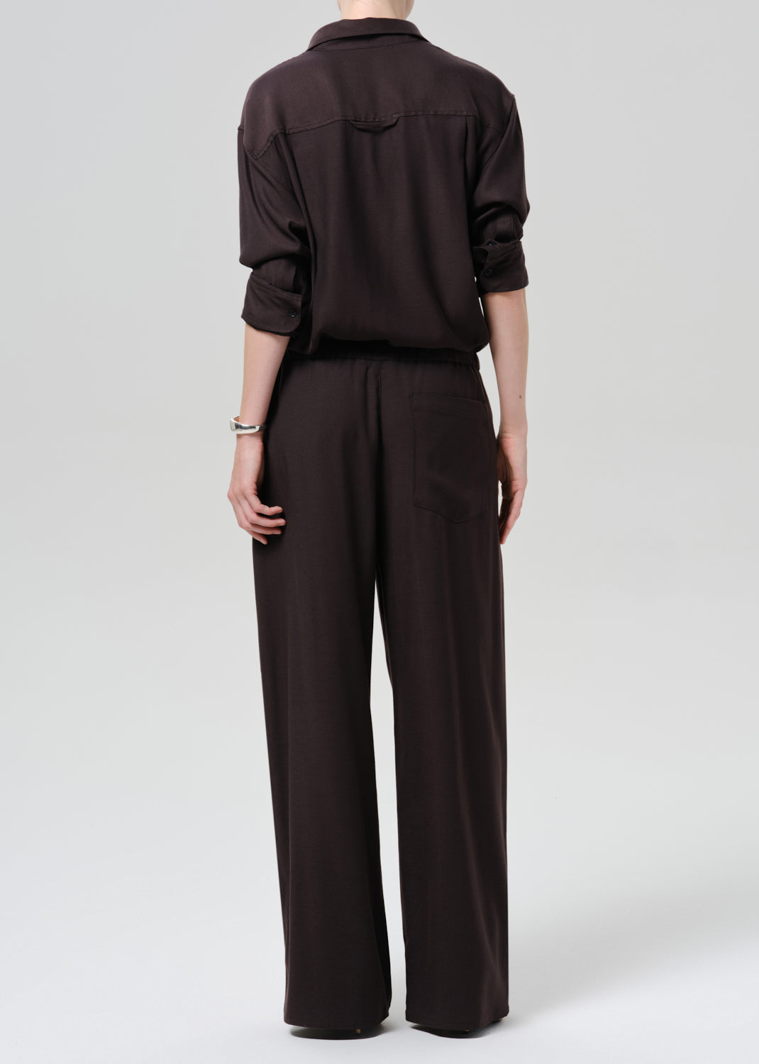 Person wearing a brown outfit on a grey background