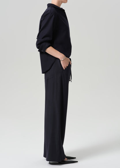 A model shown from the side wearing a dark navy blue long-sleeve top and matching wide-leg trousers against a grey background.