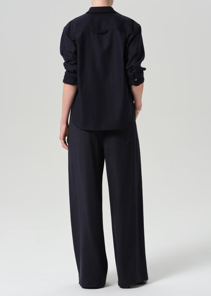 A model shown from the back wearing a dark navy blue long-sleeve button-up shirt and matching wide-leg trousers against a grey background.