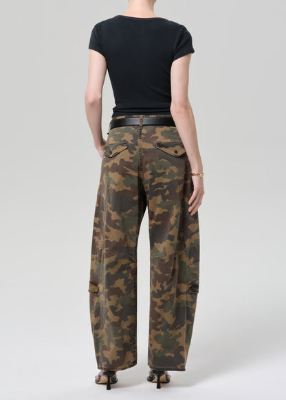 Person wearing camouflage pants and a black top on a plain background