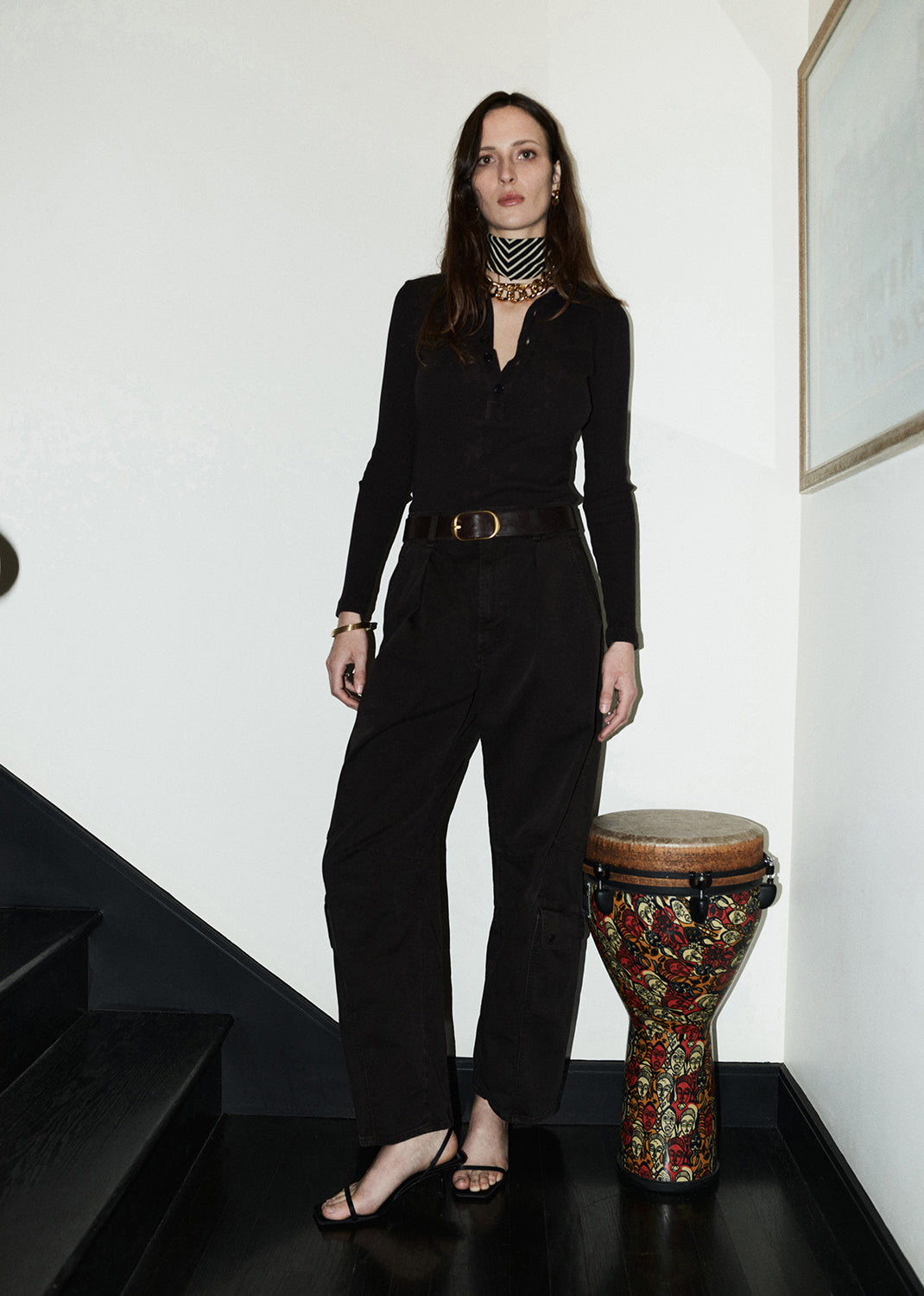 Woman in brown outfit standing next to  a staircase.
