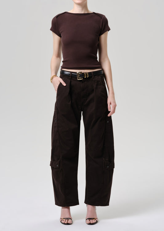 A model wearing a dark brown short-sleeve crewneck top and matching dark brown wide-leg cargo pants, styled with a black belt and gold buckle, against a grey background.
