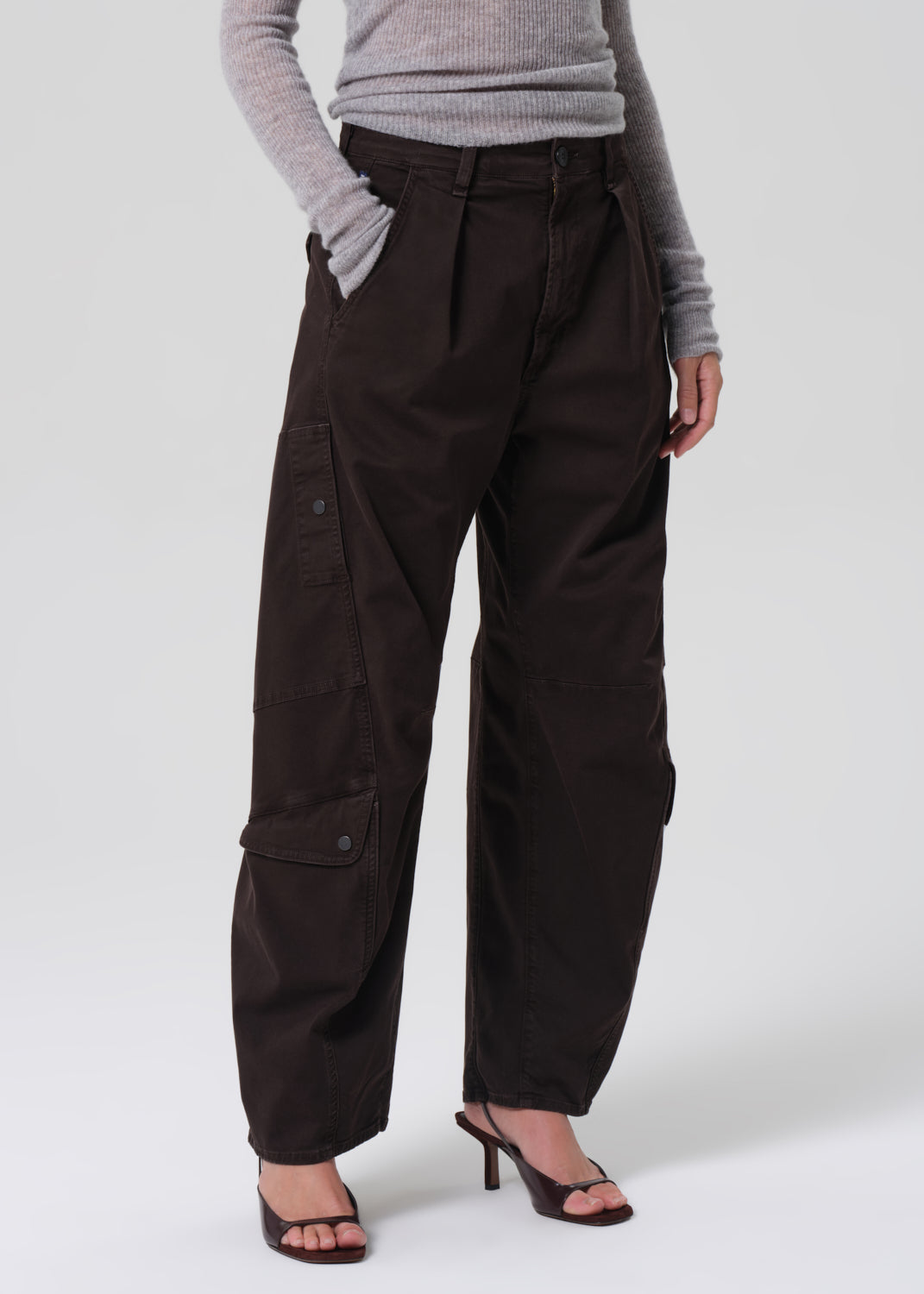Person wearing dark brown cargo pants on a grey background