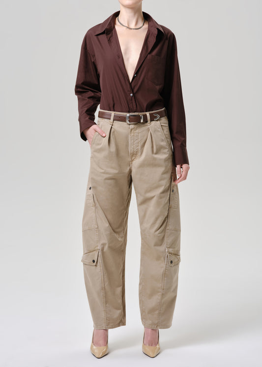 Person wearing a brown button-up shirt and beige cargo pants on a grey background.