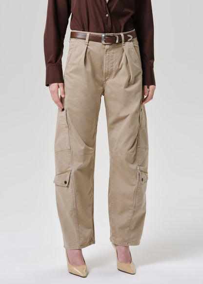 A model is shown from the waist down wearing beige cargo pants with a brown belt, a dark brown button-up shirt, and beige heels against a grey background.