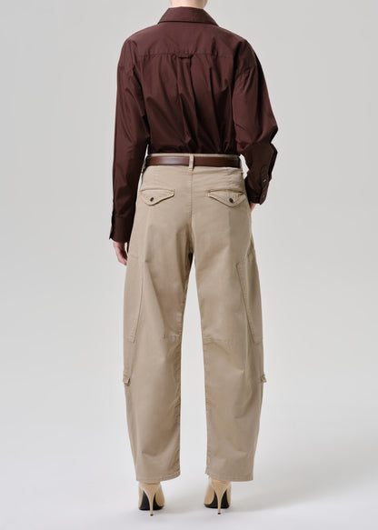 A model shown from the back wearing a dark brown long-sleeve button-down shirt tucked into beige cargo pants with a brown belt, paired with beige high heels, against a grey background.