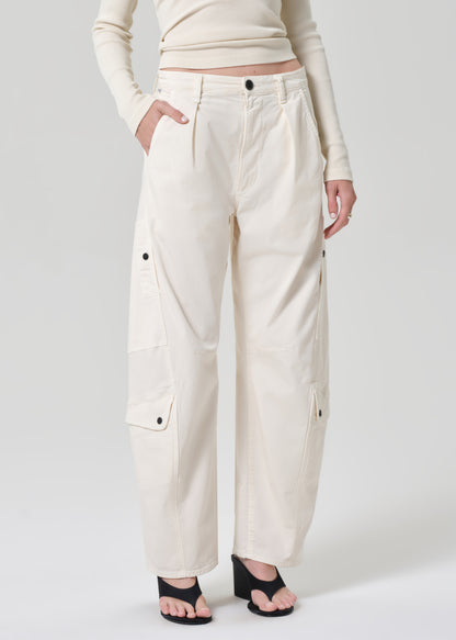 Person wearing a cream long-sleeve top and cream pants on a grey background