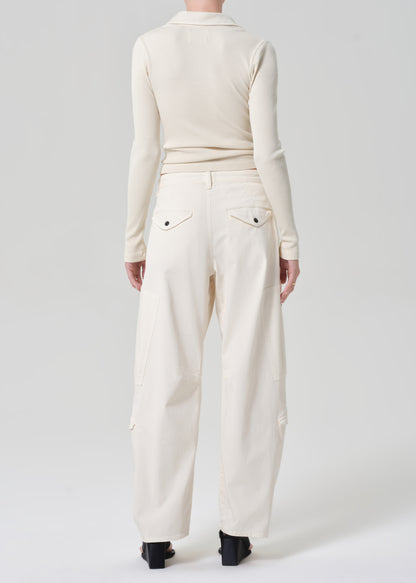 Person wearing a cream long-sleeve top and cream pants on a grey background