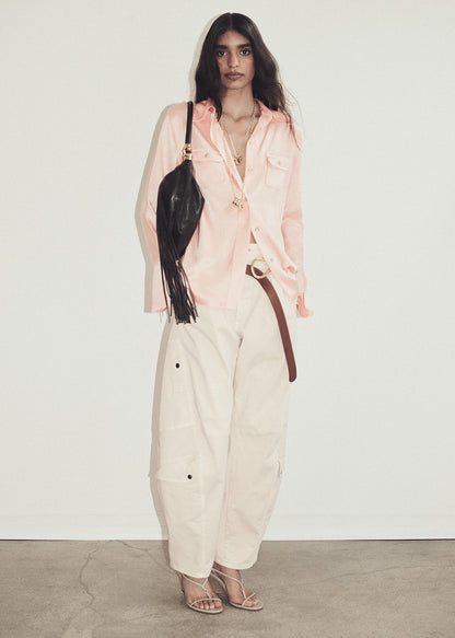 Person wearing a pink shirt and light pink pants on a grey background