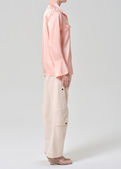 Person wearing a pink shirt and light pink pants on a grey background