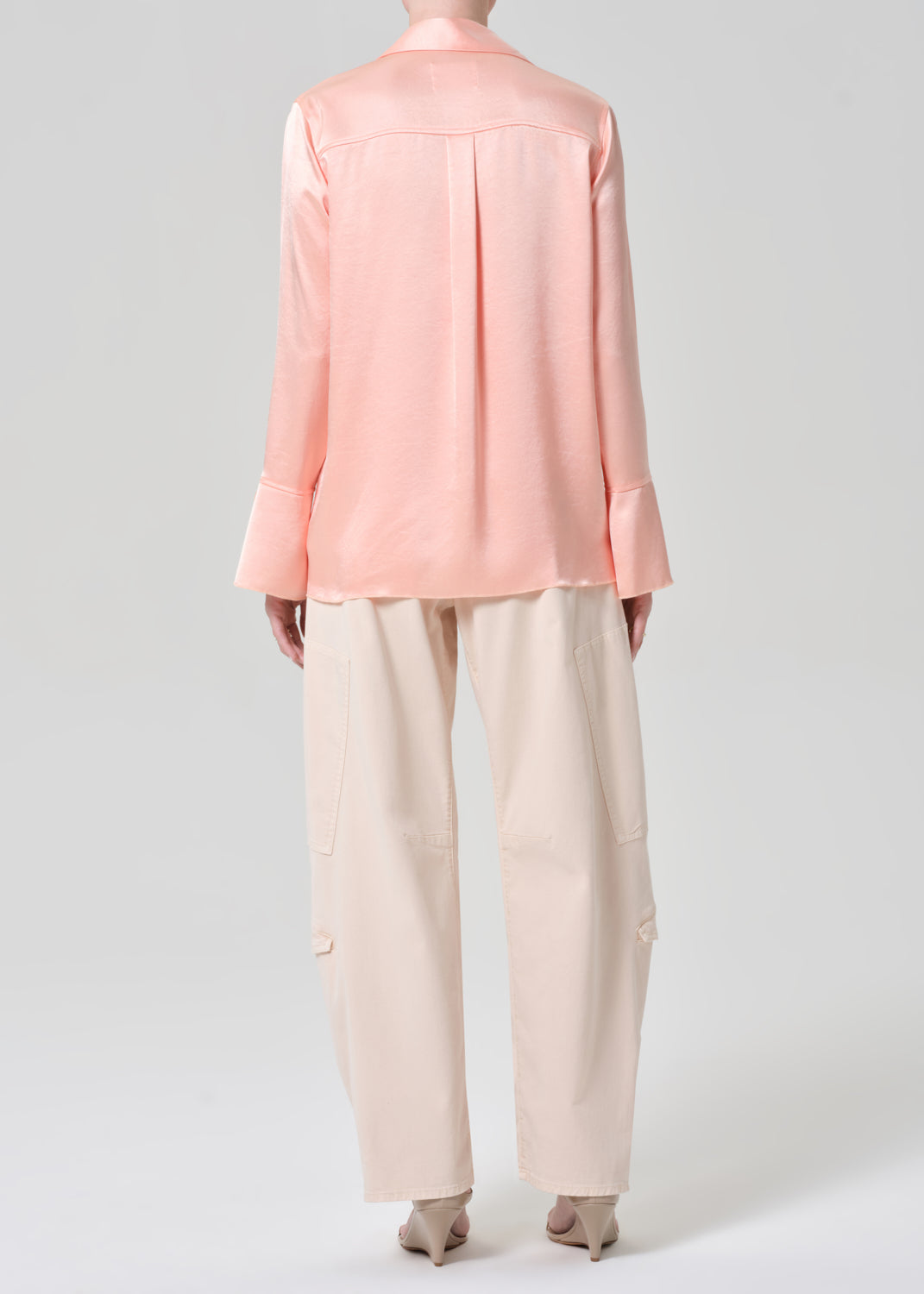 Person wearing a pink shirt and light pink pants on a grey background