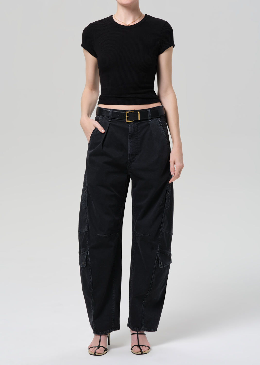 Person wearing a black tee and black cargo pants on a plain background