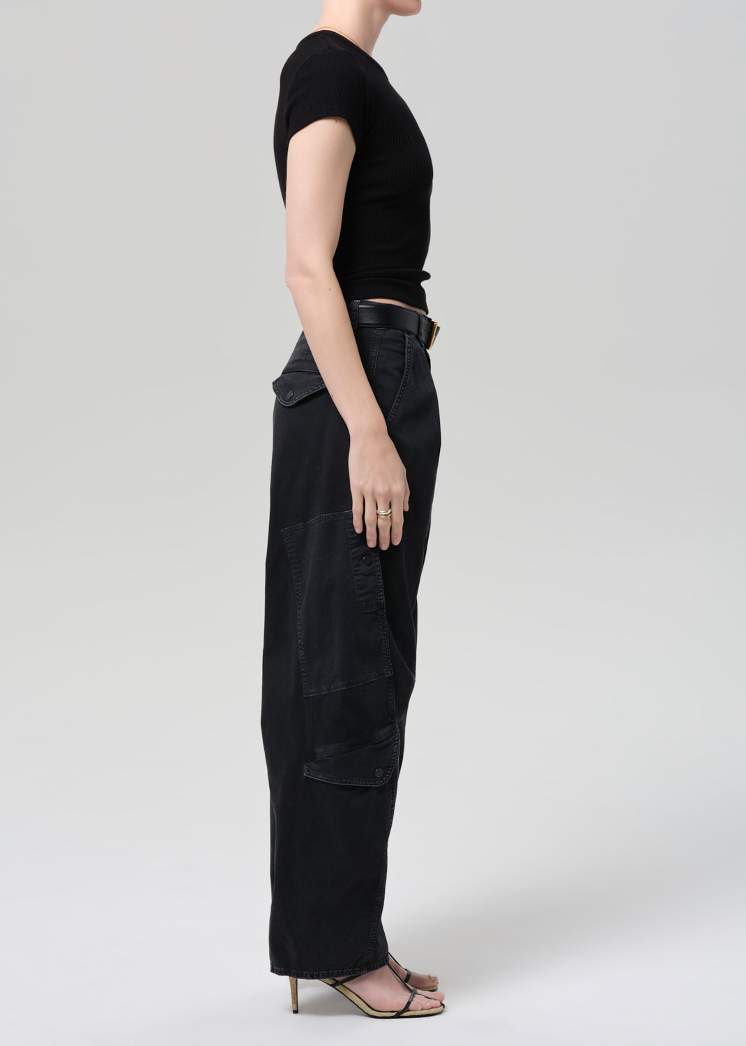 Person wearing a black tee and black cargo pants on a plain background