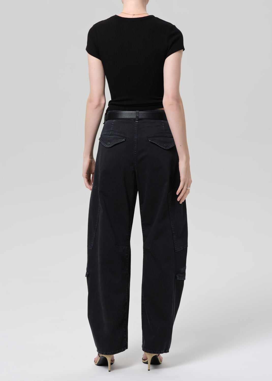 Person wearing a black tee and black cargo pants on a plain background