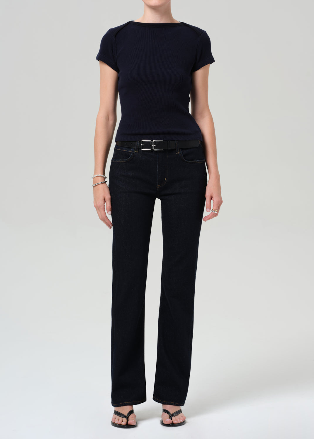 Person wearing a navy t-shirt and dark jeans on a plain background