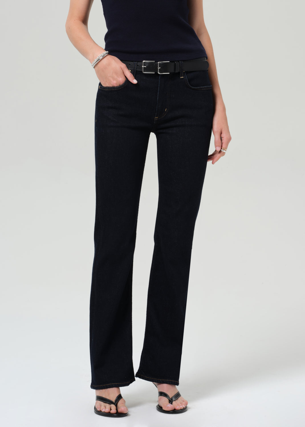 Person wearing a navy t-shirt and dark jeans on a plain background