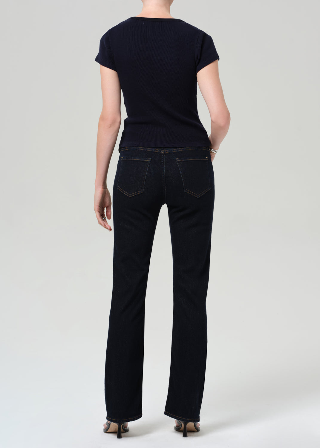 Person wearing a navy t-shirt and dark jeans on a plain background