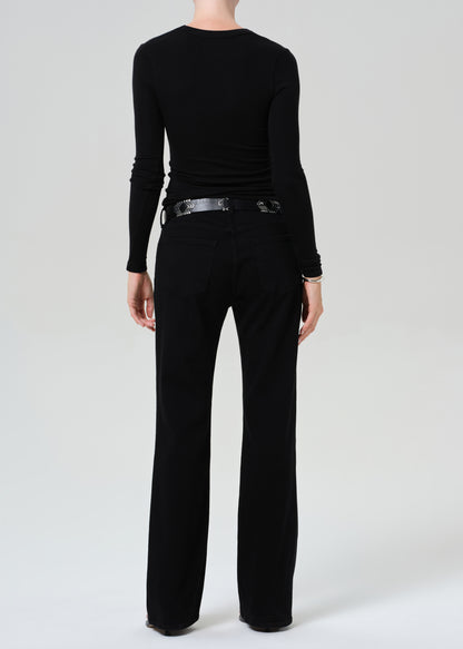 Person wearing a black long-sleeve top and black jean on a plain background