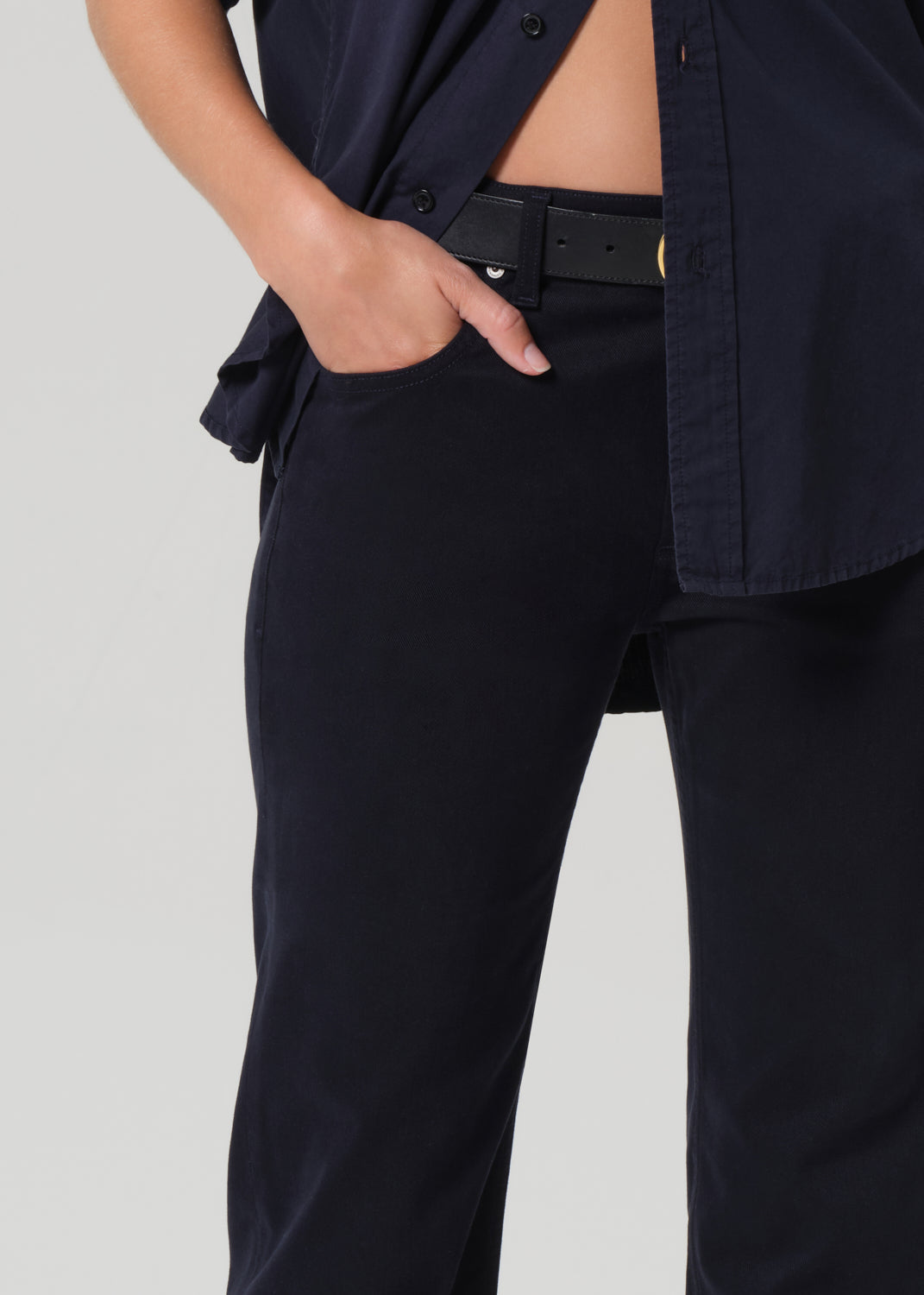 Person wearing a navy shirt and navy pants on a light gray background