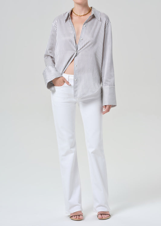 Person wearing a striped shirt and white jeans on a plain background