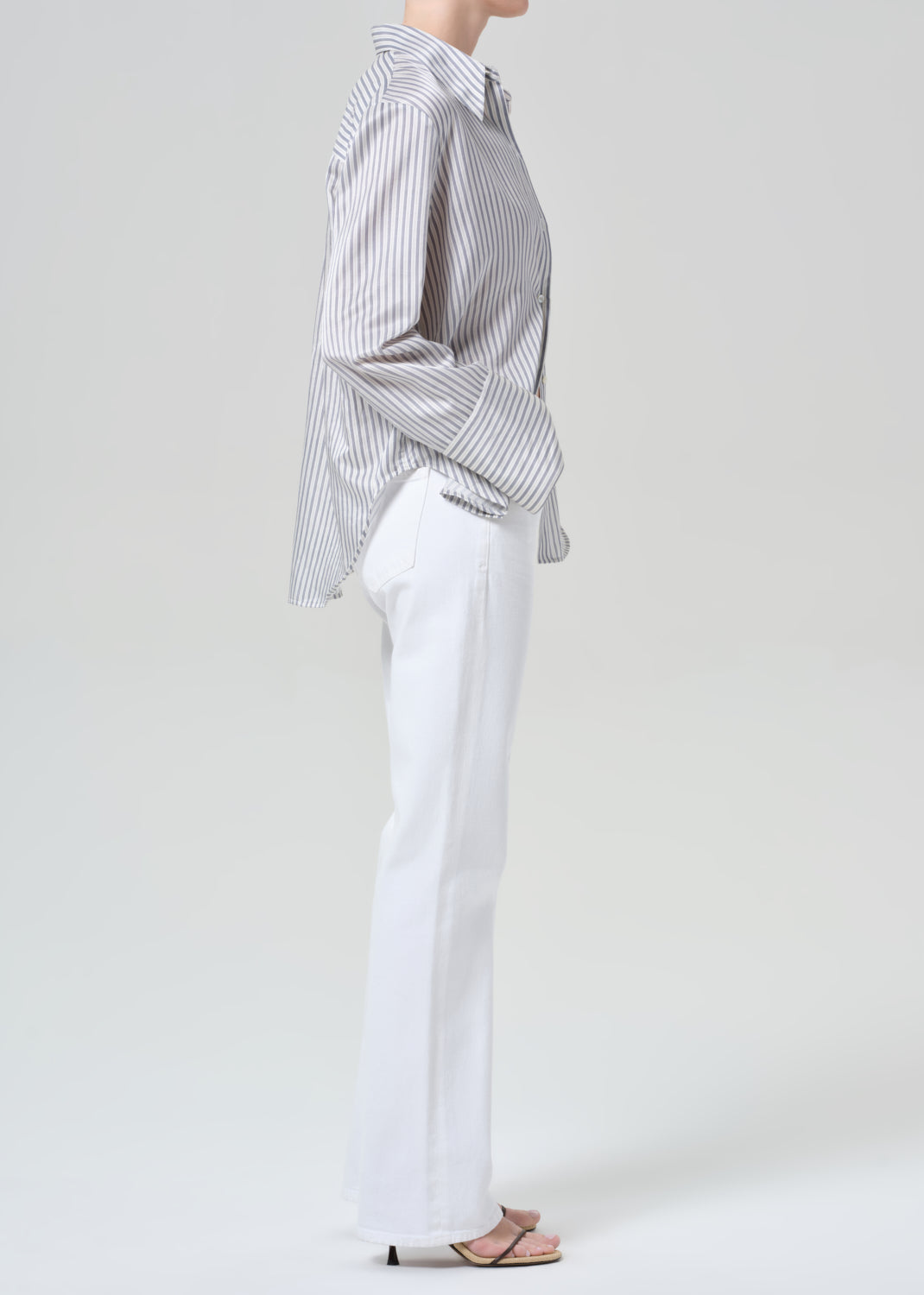 Person wearing a striped shirt and white jeans on a plain background