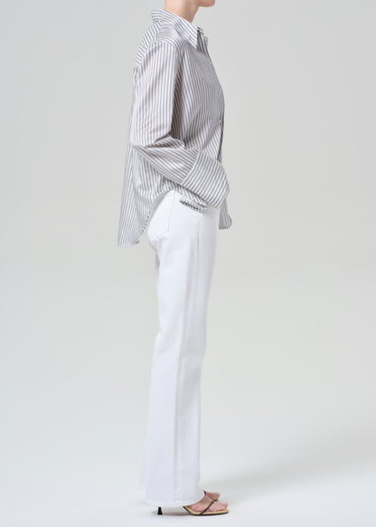 Person wearing a striped shirt and white jeans on a plain background