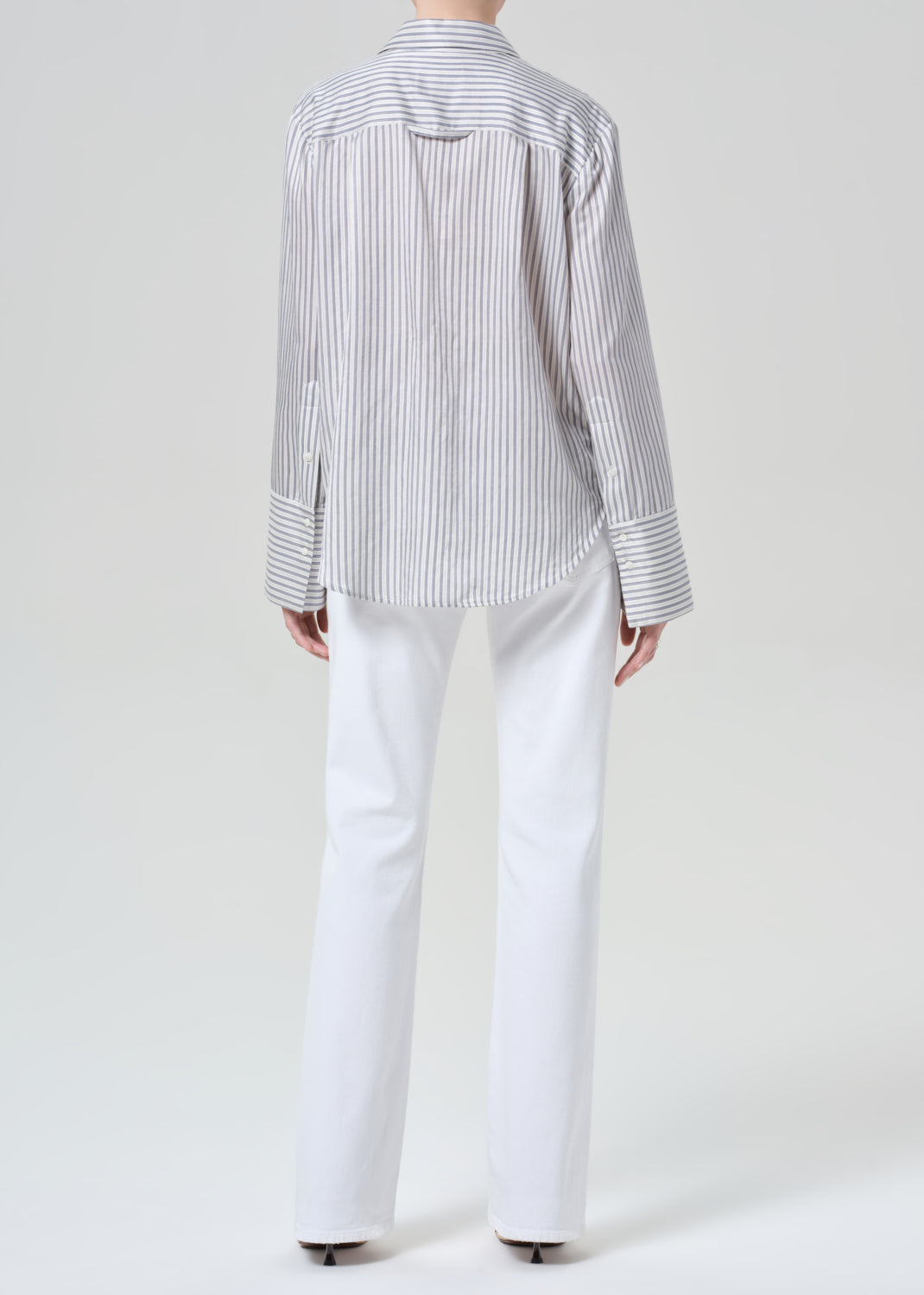 Person wearing a striped shirt and white jeans on a plain background