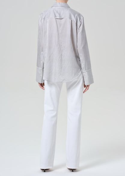 Person wearing a striped shirt and white jeans on a plain background