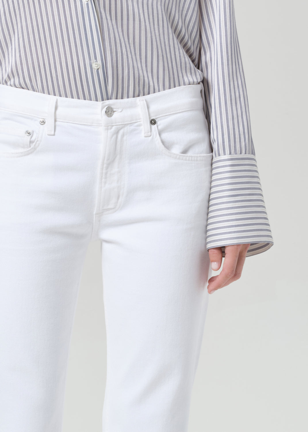 Person wearing a striped shirt and white jeans on a plain background
