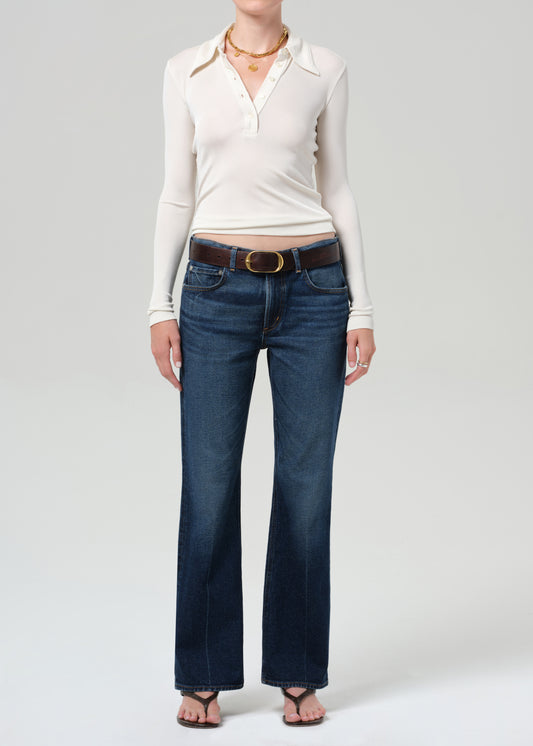 Person wearing a white long-sleeve shirt and blue jeans on a plain background