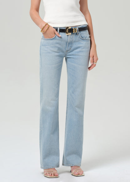 Person wearing light blue jeans and a white top on a plain background