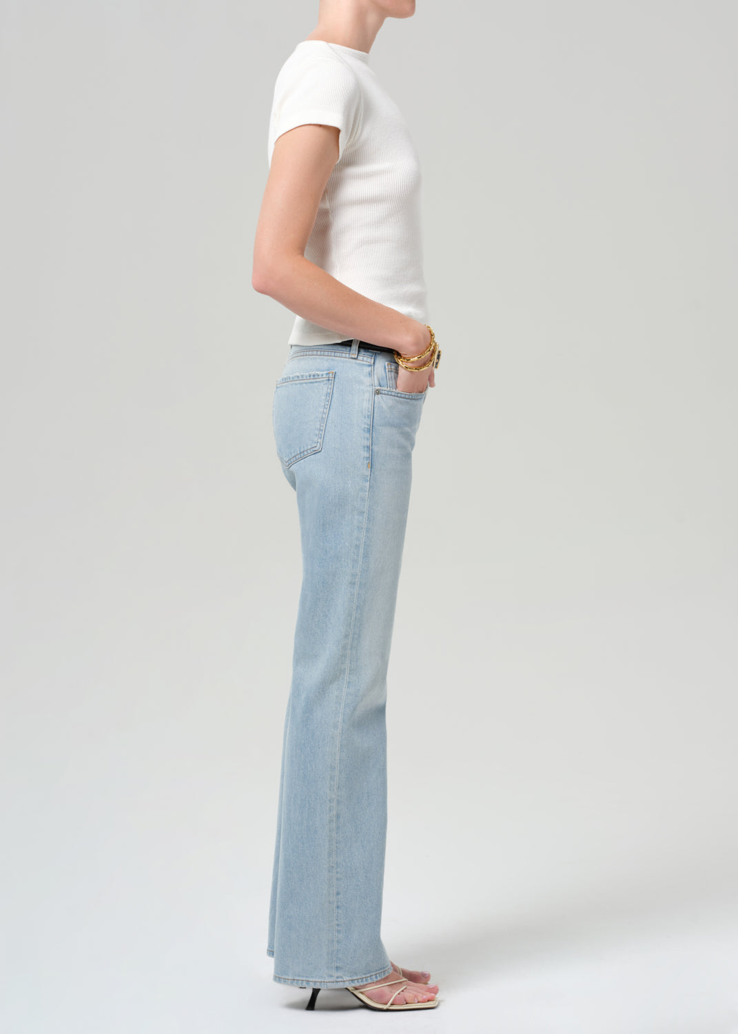 Person wearing light blue jeans and a white top on a plain background