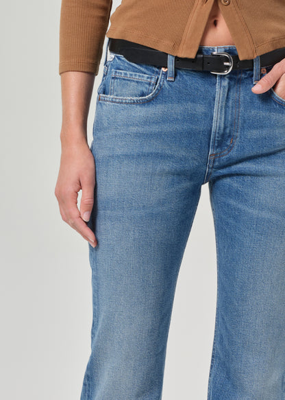 Person wearing blue jeans with a black belt on a plain background