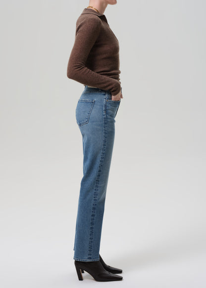 Person wearing blue jeans and a brown sweater on a grey background