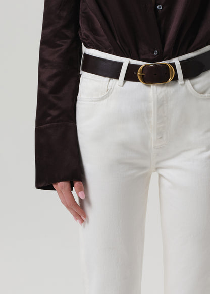 Person wearing a brown shirt and white pants on a plain background