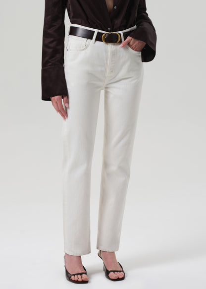 Person wearing a brown shirt and white pants on a plain background