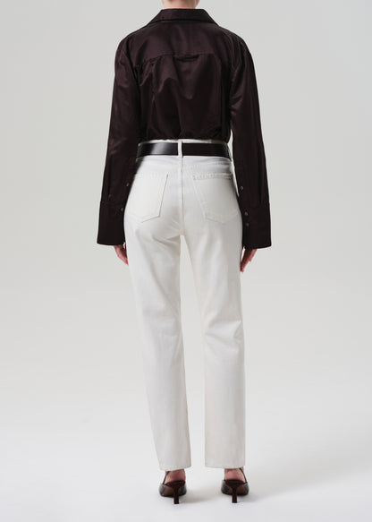 Person wearing a brown shirt and white pants on a plain background