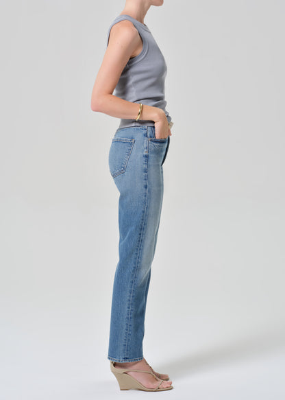 Person wearing a sleeveless top and jeans on a plain background