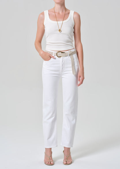 Person wearing a white tank top and white jeans on a plain background