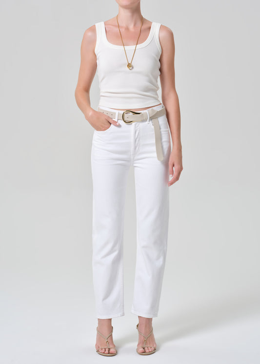 Person wearing a white tank top and white jeans on a plain background