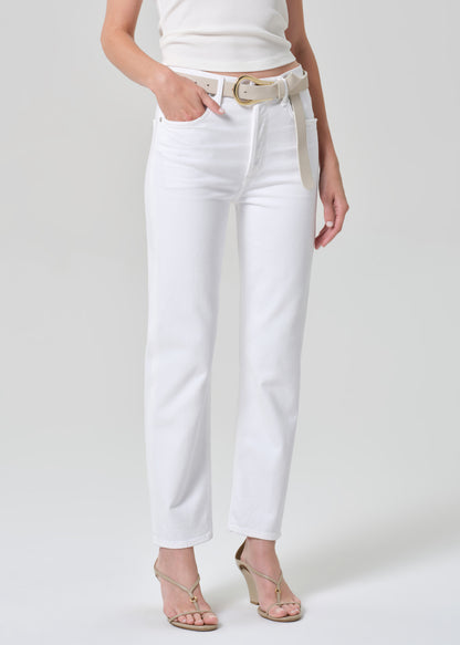 Person wearing a white tank top and white jeans on a plain background